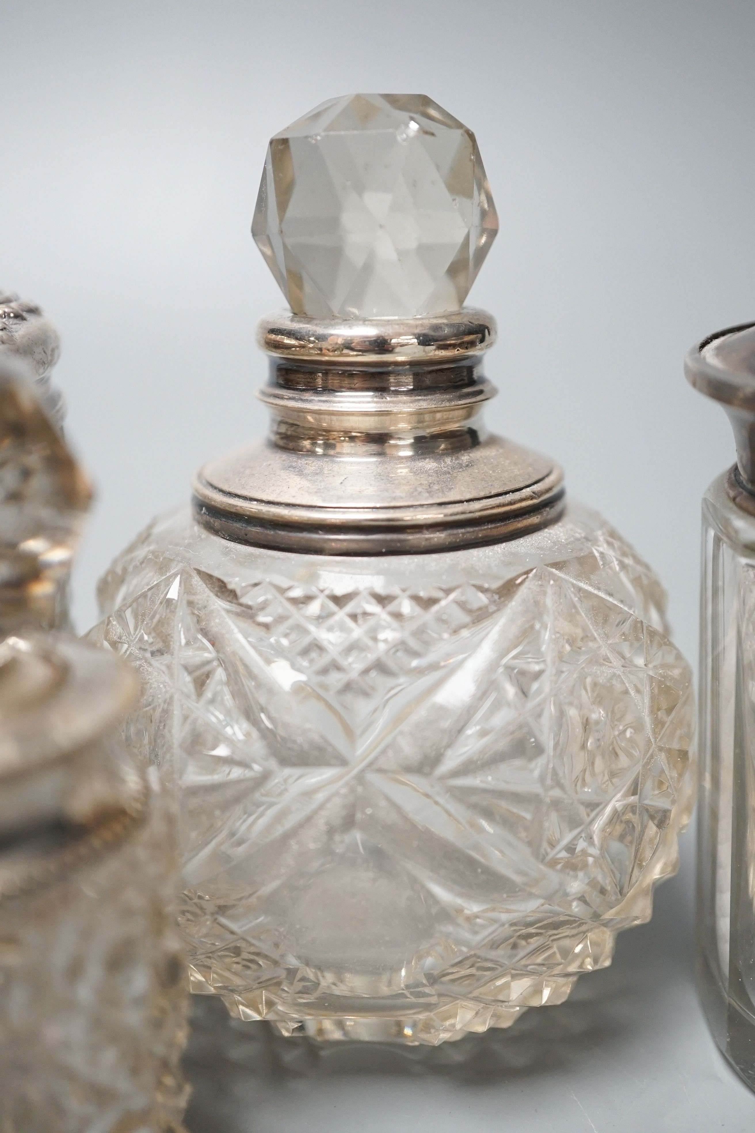 A circular embossed silver box and six silver mounted glass toilet bottles.